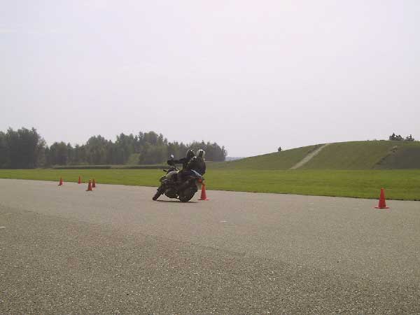 Motorrijder met achteropzitter slalomt om pilonnen